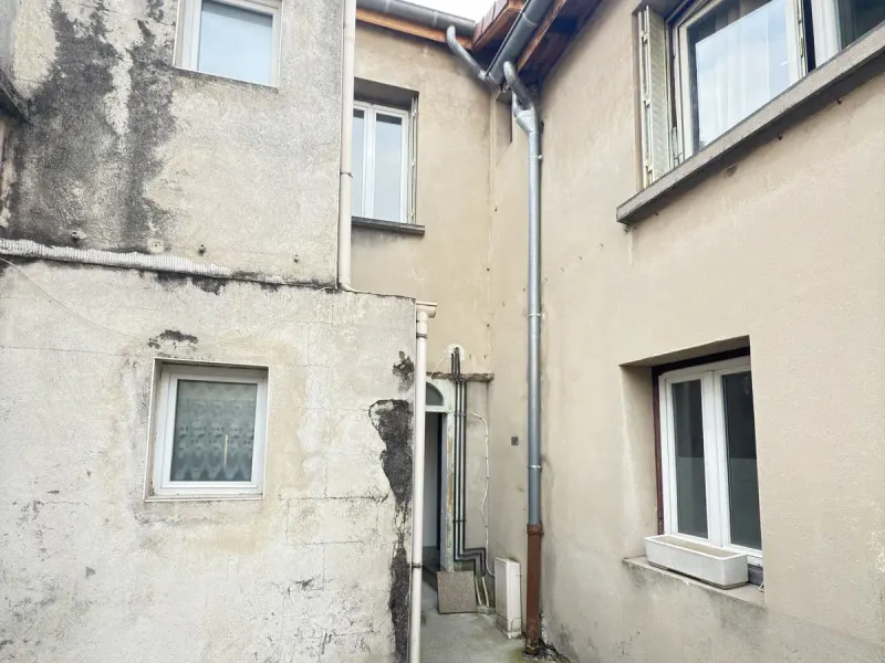 Cour d'immeuble avant peinture, murs gris et sales