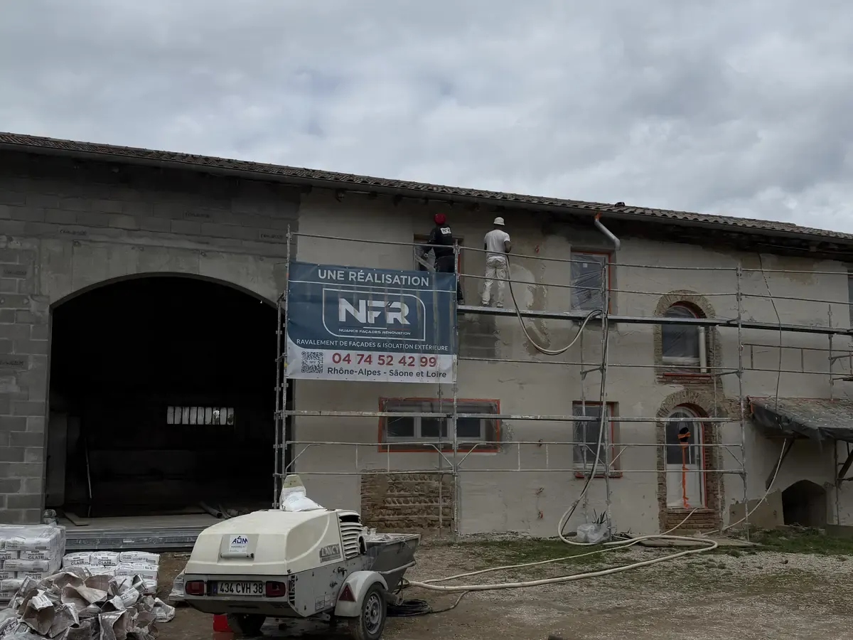 Ferme en pisé sous échafaudage, banderole NFR, machine à projeter l'enduit au sol